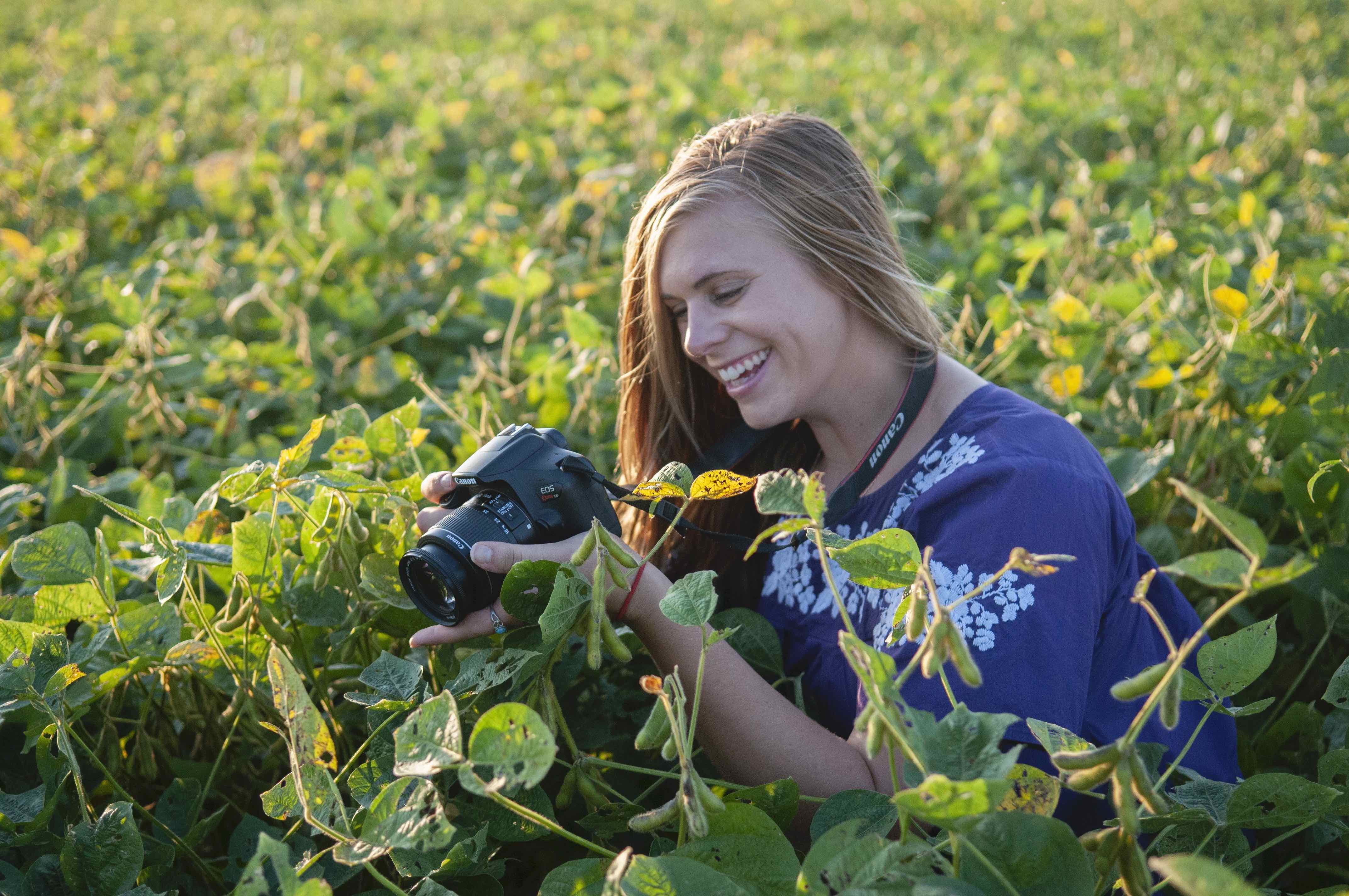 Image of a student in a field with camera.